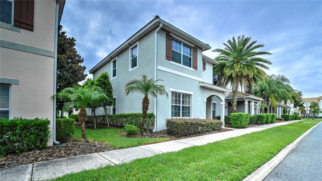 A two-story light blue residential building with palm trees and a sidewalk in front — 4882 CLOCK TOWER DRIVE, KISSIMMEE, FL