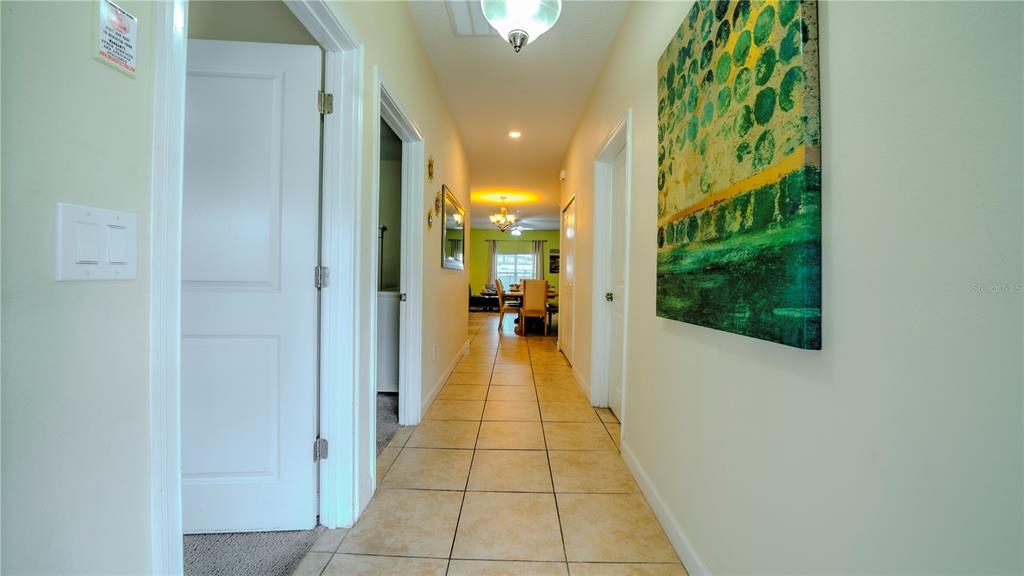 A hallway with beige tile flooring leads to a dining area with a table — 4882 CLOCK TOWER DRIVE, KISSIMMEE, FL