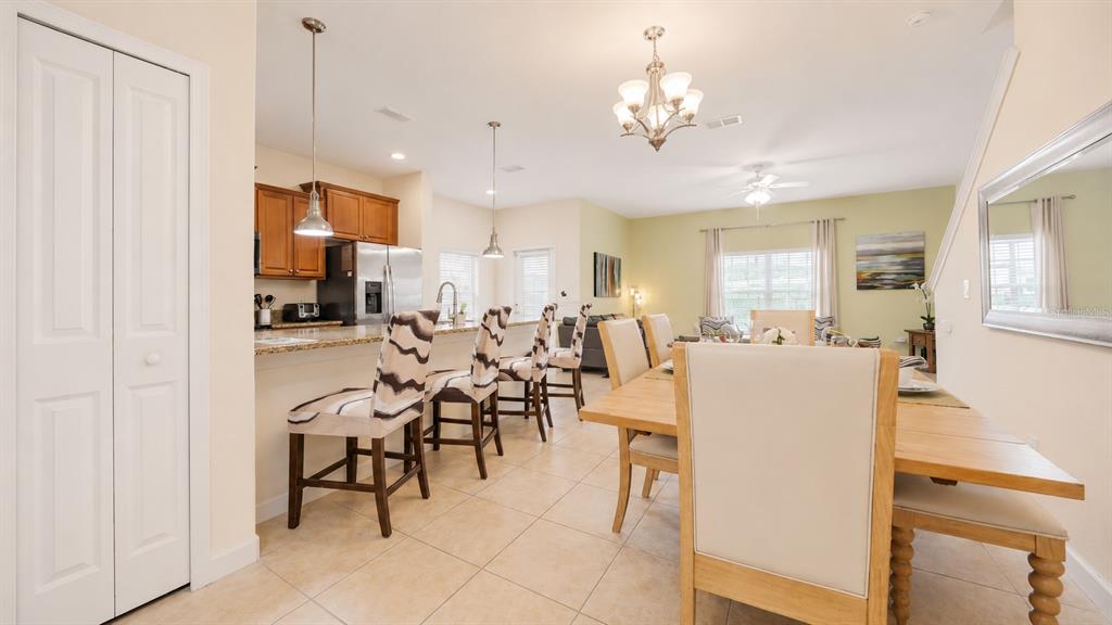An open-concept kitchen and dining area features tile flooring, wood cabinets, and bar seating — 4882 CLOCK TOWER DRIVE, KISSIMMEE, FL