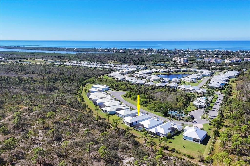 An aerial view shows a residential neighborhood with white-roofed houses surrounded by trees and water — 8936 CONCH AVENUE, PLACIDA, FL