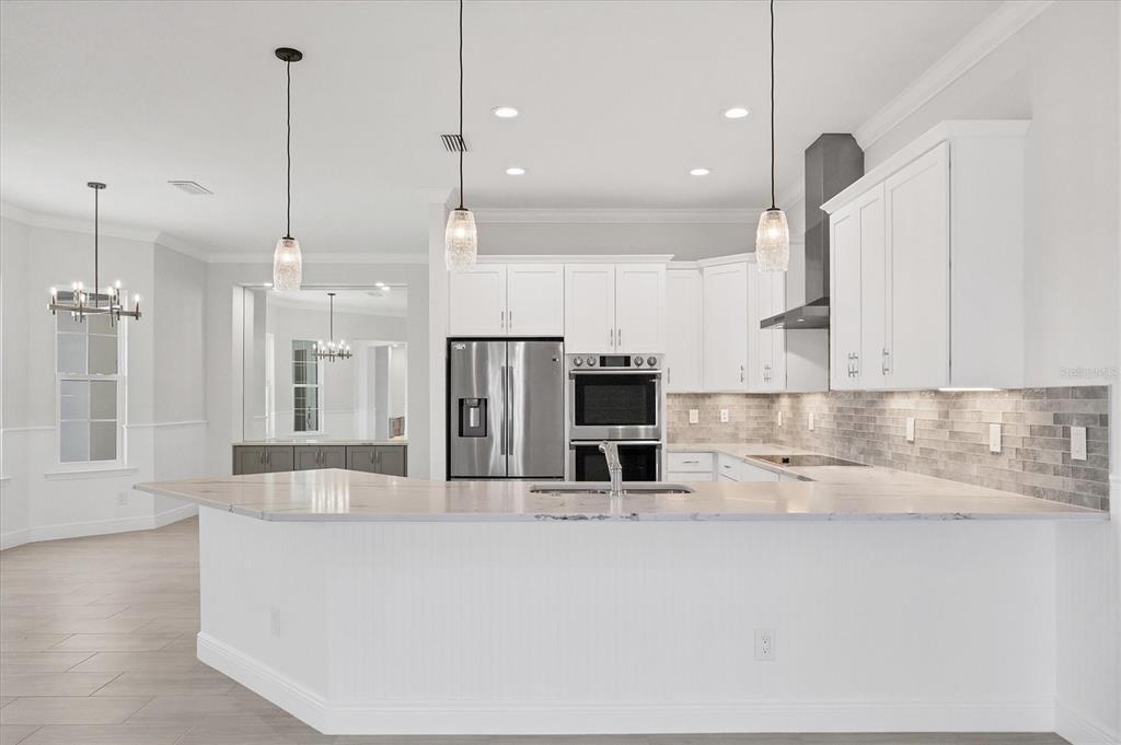 A kitchen with white cabinets, stainless steel appliances, and a marble-topped peninsula island — 8936 CONCH AVENUE, PLACIDA, FL