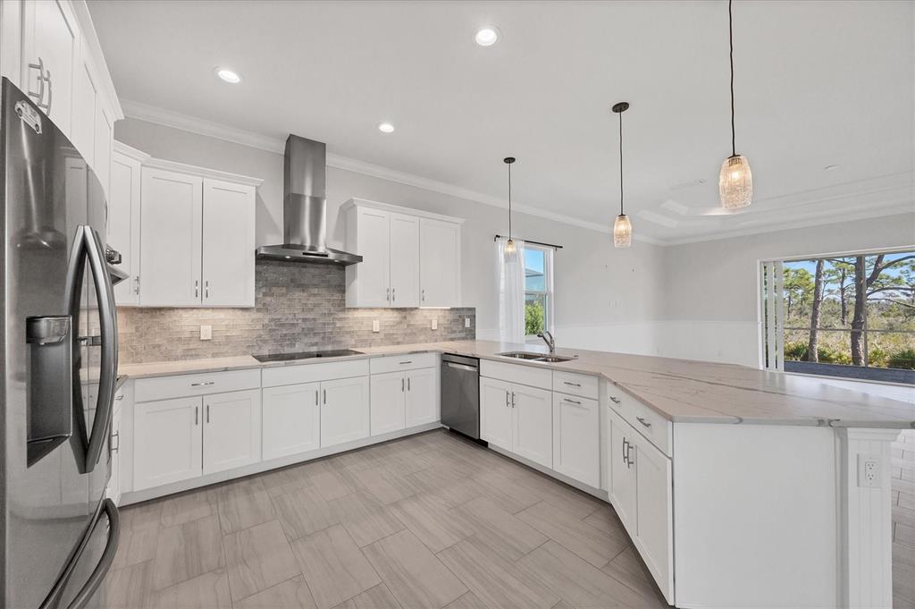 A modern kitchen features white cabinets, stainless steel appliances, a tile backsplash, and an island — 8936 CONCH AVENUE, PLACIDA, FL