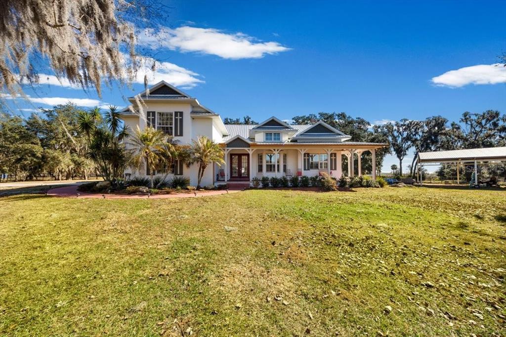 A two-story white house with a metal roof and a large front porch — 15104 COUNTY ROAD 48, ASTATULA, FL