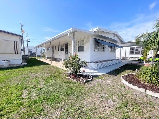 A white mobile home with a covered porch sits on a grassy lot — 816 TURF, VENICE, FL