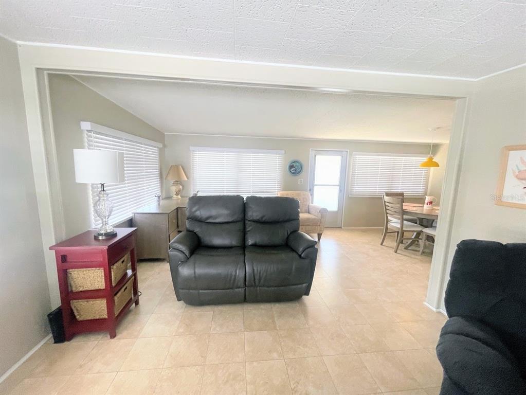 A living room features a dark leather loveseat, tile flooring, and a red side table — 816 TURF, VENICE, FL