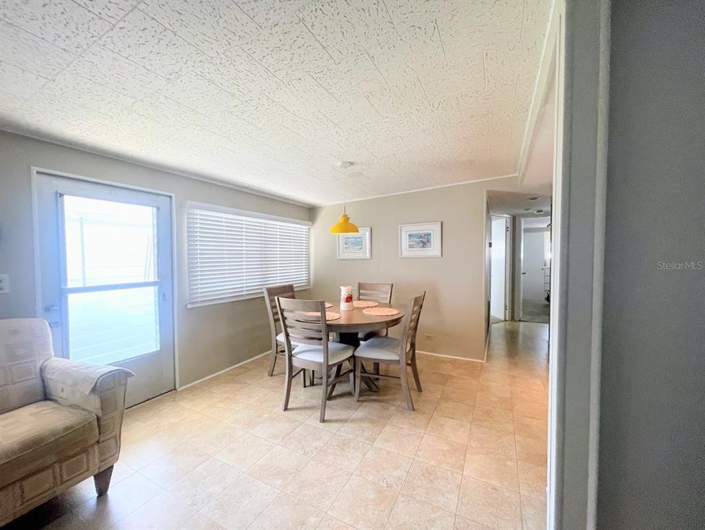 A dining area features a round table with four chairs, tile flooring, and a yellow pendant — 816 TURF, VENICE, FL