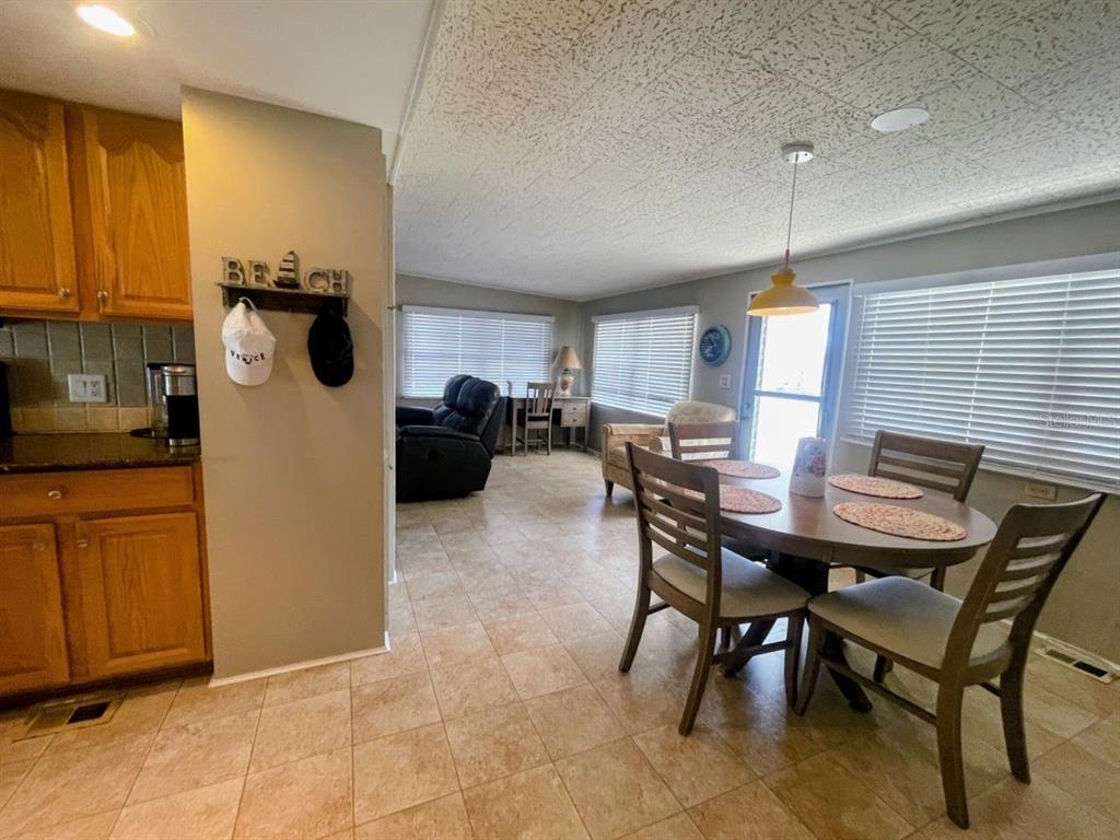 A dining area with a wooden table and chairs sits adjacent to a kitchen — 816 TURF, VENICE, FL