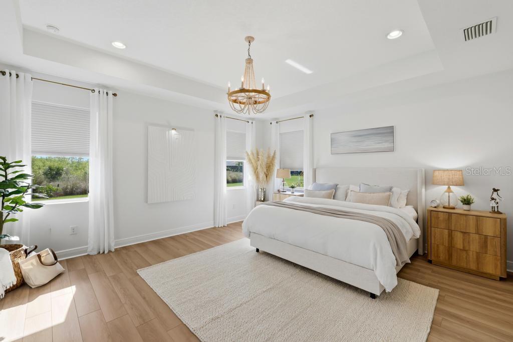A bright bedroom features a king bed, wood flooring, a chandelier, and large windows — 17731 SAVORY MIST CIRCLE, BRADENTON, FL