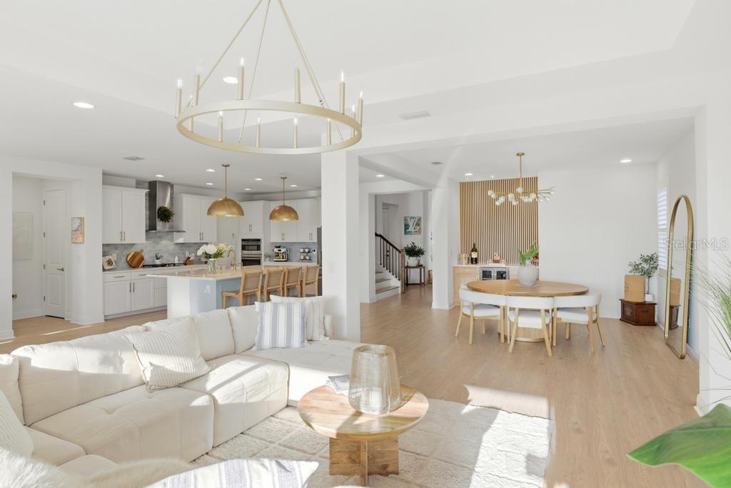 An open-concept living room, dining area, and kitchen with white cabinetry and light wood flooring — 17731 SAVORY MIST CIRCLE, BRADENTON, FL