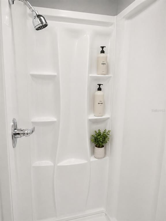 A white fiberglass shower stall features a chrome shower head, handle, and built-in storage shelves — 2630 SW 55TH AVENUE, WEST PARK, FL