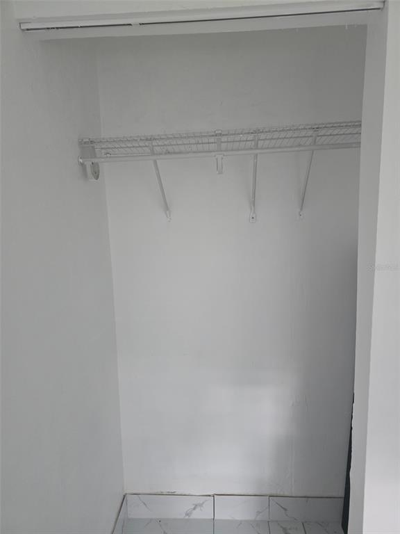 A small closet features a white wire shelf and light-colored tile flooring — 2630 SW 55TH AVENUE, WEST PARK, FL