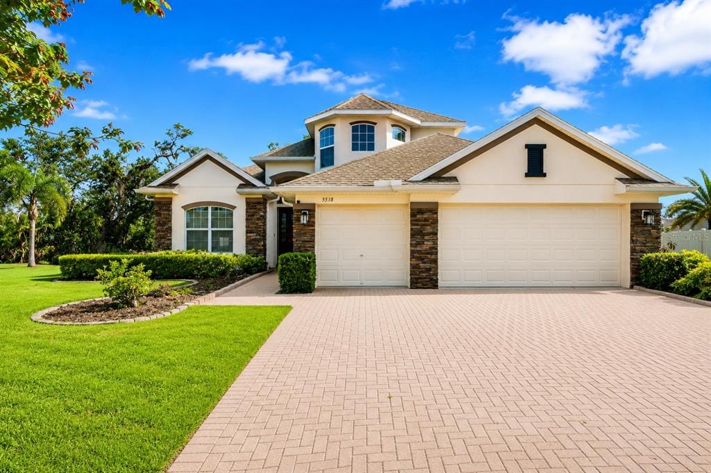 A two-story suburban house with a stone-accented facade, a three-car garage, and a paved driveway — 5518 72ND TERRACE E, ELLENTON, FL
