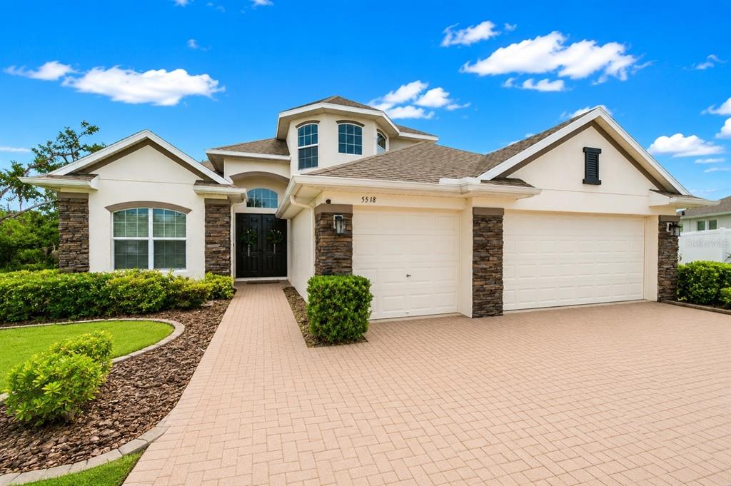 A single-story house with a stone facade, a paved driveway, and a two-car garage — 5518 72ND TERRACE E, ELLENTON, FL