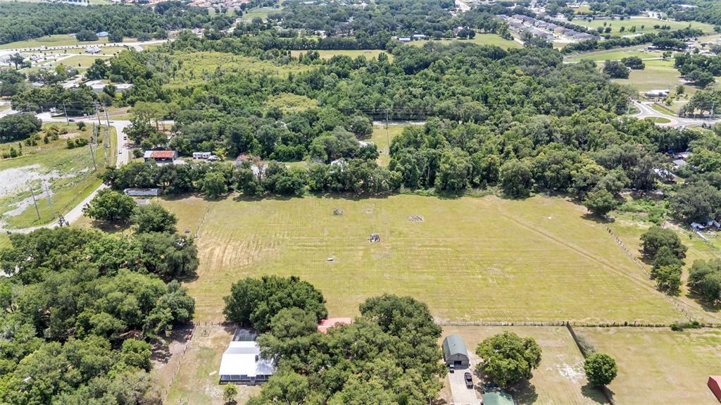 An aerial view shows a large, open grassy field bordered by trees and residential structures — 3146 MOUNT TABOR ROAD, LAKELAND, FL