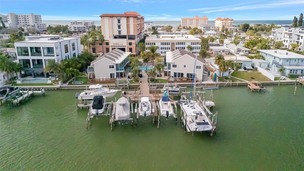 An aerial view of a waterfront property with a private dock and several moored boats — 673 BAY ESPLANADE UNIT 204, CLEARWATER BEACH, FL