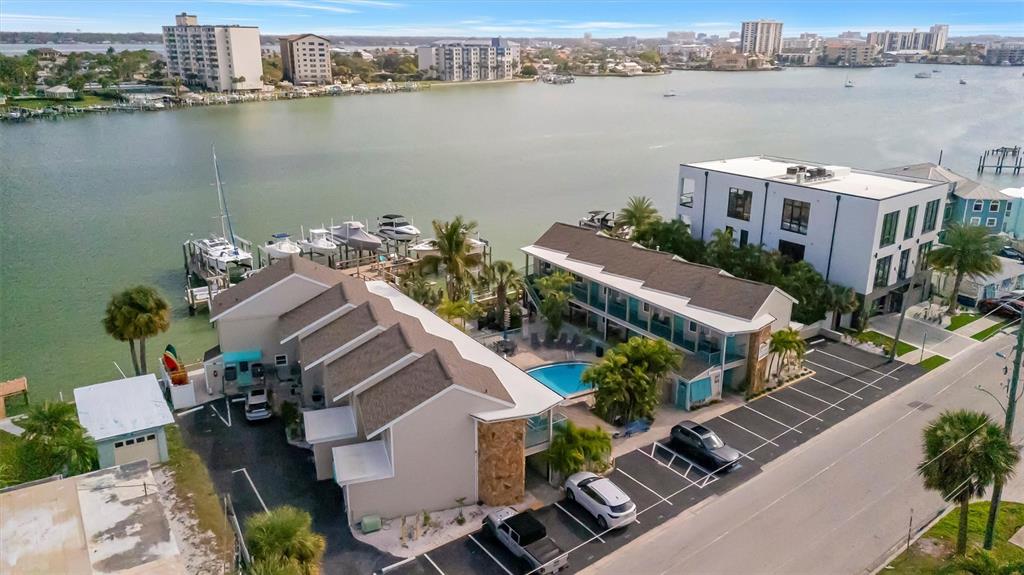 An aerial view shows a waterfront hotel with a pool, parking lot, and boat docks — 673 BAY ESPLANADE UNIT 204, CLEARWATER BEACH, FL