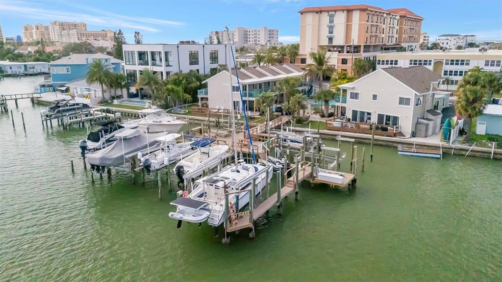 An aerial view shows several boats docked at a pier beside waterfront residential buildings — 673 BAY ESPLANADE UNIT 204, CLEARWATER BEACH, FL