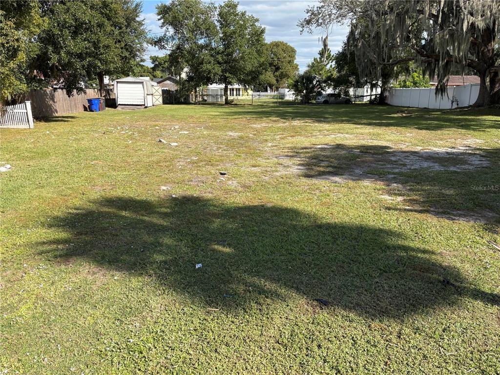 A large, grassy, fenced-in backyard features a detached shed and mature trees — 1113 MICHIGAN AVENUE, ST CLOUD, FL