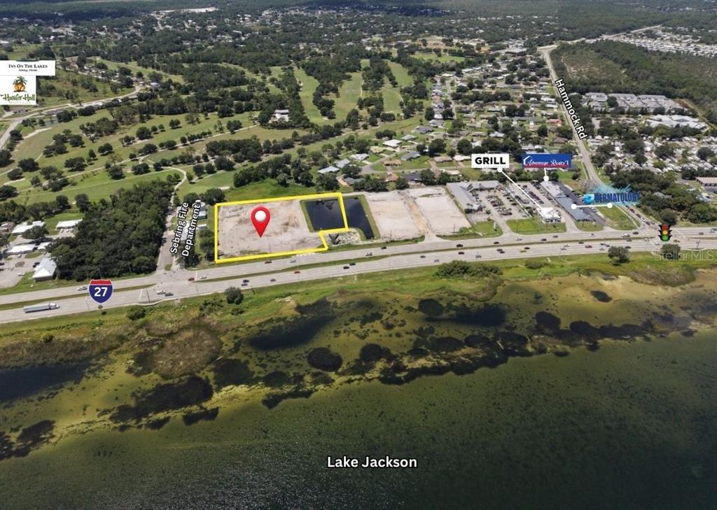An aerial view shows a vacant lot outlined in yellow next to Lake Jackson — 1025 US-27 S, SEBRING, FL