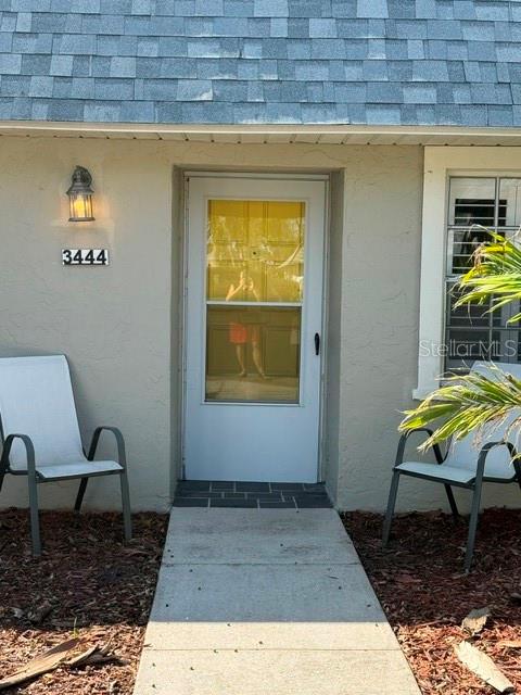 A white front door with a glass storm door is flanked by two chairs — 3444 TROPHY BOULEVARD, NEW PORT RICHEY, FL
