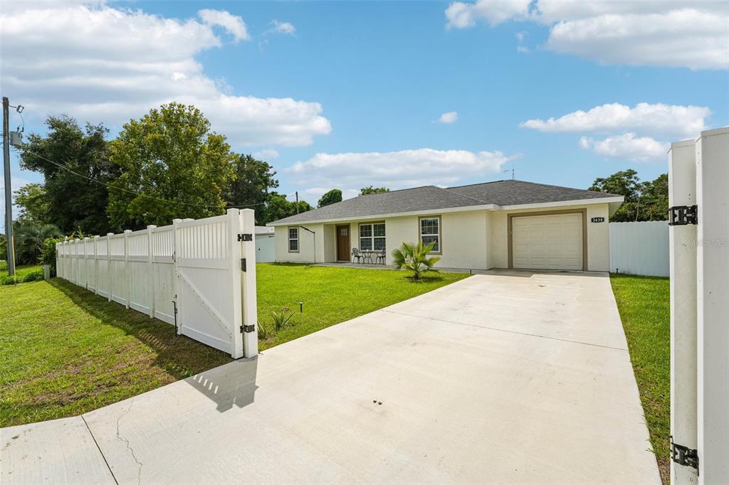 A single-story house with a white exterior, a concrete driveway, and a white vinyl fence — 3638 SE 137TH STREET, SUMMERFIELD, FL