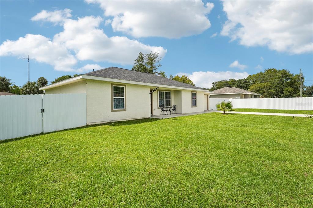 A single-story house with a white fence and a grassy backyard under a blue sky — 3638 SE 137TH STREET, SUMMERFIELD, FL