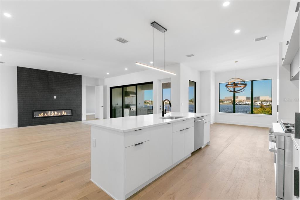 A modern kitchen with a white island and fireplace overlooks a water view — 1810 4TH STREET E, PALMETTO, FL
