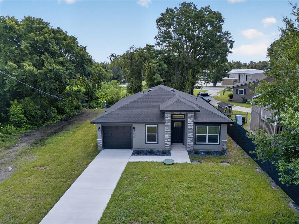 An aerial view shows a single-story gray house with a stone-accented entryway and driveway — 2225 MCCARTHY AVENUE, SANFORD, FL