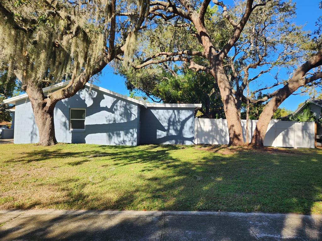 A light blue concrete block house sits behind a grassy lawn under large oak trees — 800 DIANE CIRCLE, CASSELBERRY, FL