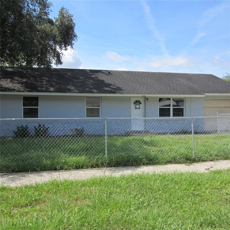 A single-story house with a light blue exterior, a dark shingled roof, and a chain-link fence — 520 W ELLA J GILMORE STREET, APOPKA, FL
