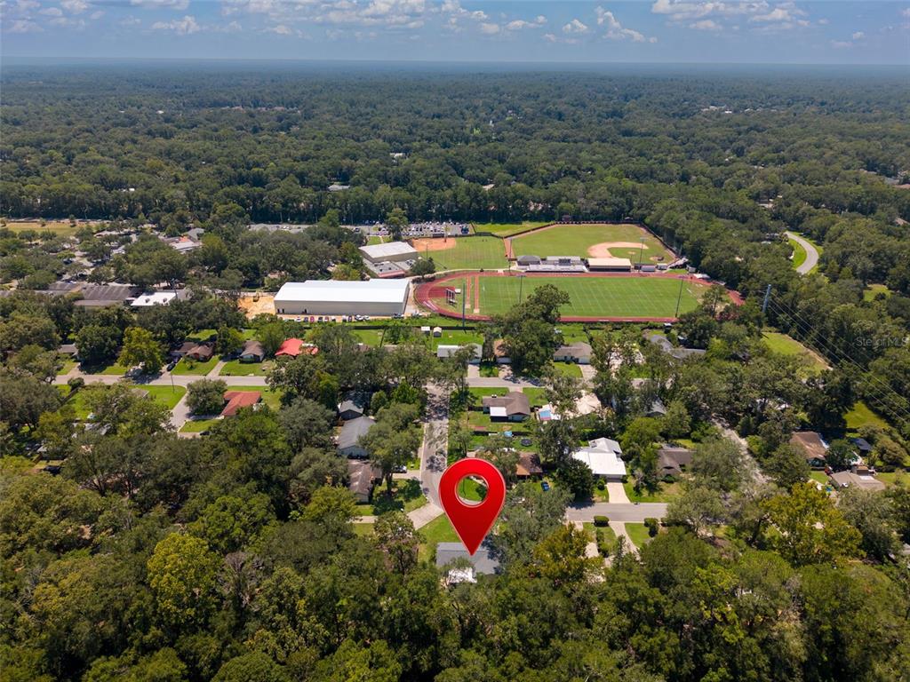 An aerial view shows a house marked with a red pin near a sports complex — 8114 SW 12TH PLACE, GAINESVILLE, FL