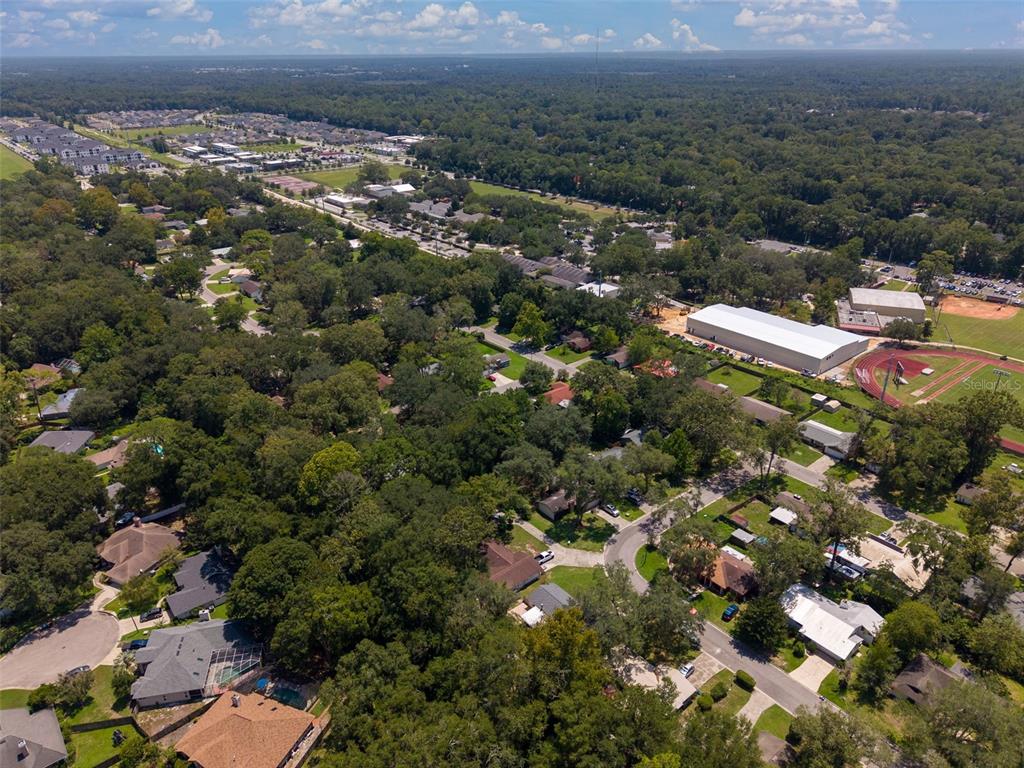 An aerial view shows a single-family home outlined in white, situated on a wooded lot — 8114 SW 12TH PLACE, GAINESVILLE, FL