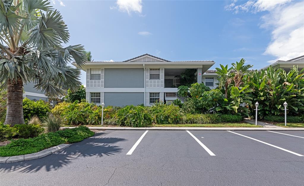 A two-story apartment building with a parking lot in the foreground and lush landscaping — 1249 EDGEWATER CIRCLE UNIT 73, BRADENTON, FL