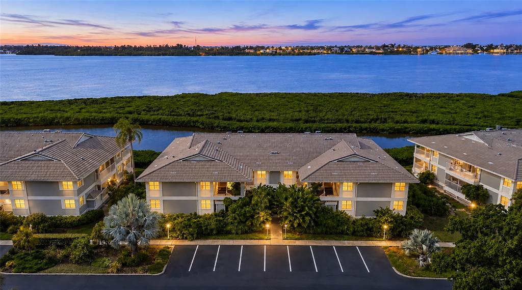 An aerial view shows three multi-story apartment buildings with parking spaces in front at sunset — 1249 EDGEWATER CIRCLE UNIT 73, BRADENTON, FL