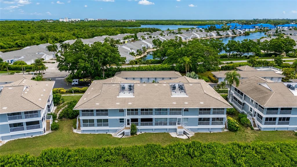 An aerial view shows multi-story residential buildings with light blue siding and tan roofs — 1249 EDGEWATER CIRCLE UNIT 73, BRADENTON, FL