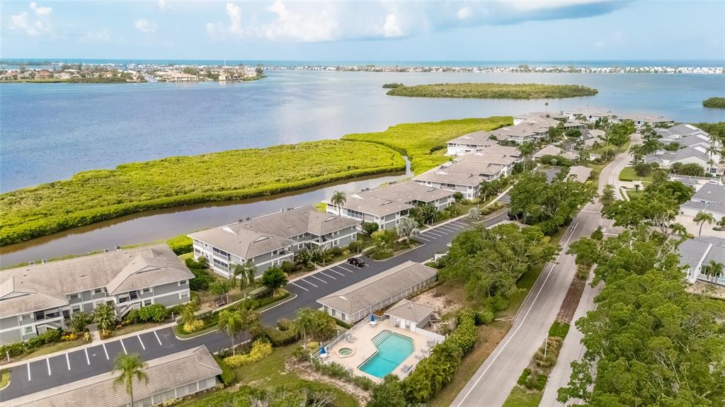 An aerial view shows multi-story residential buildings, a swimming pool, and parking lots near water — 1249 EDGEWATER CIRCLE UNIT 73, BRADENTON, FL
