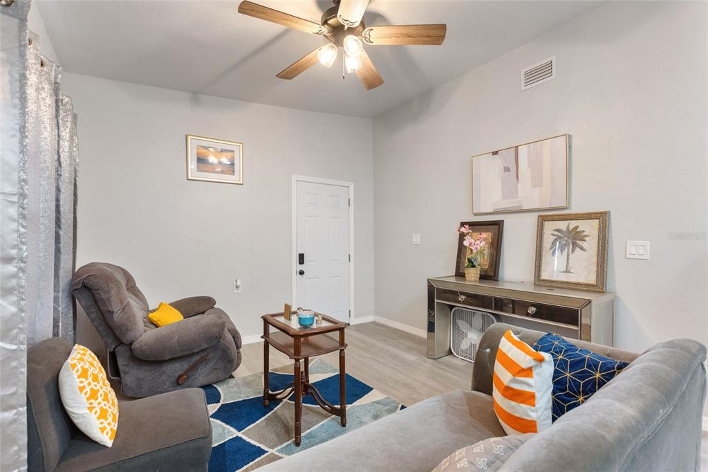 A living room features gray furniture, a blue and gray area rug, and a ceiling fan — 1495 PENNIWA STREET, INTERCESSION CITY, FL