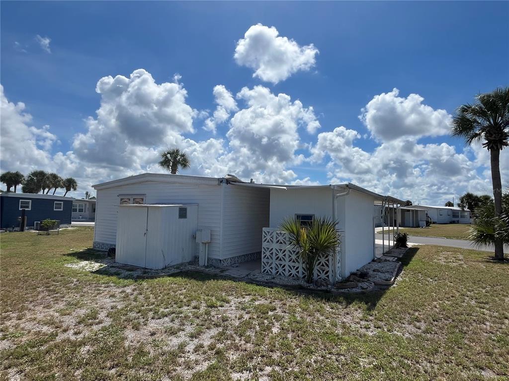 A white mobile home with a metal storage shed and decorative lattice screen exterior — 633 COMO DRIVE, VENICE, FL