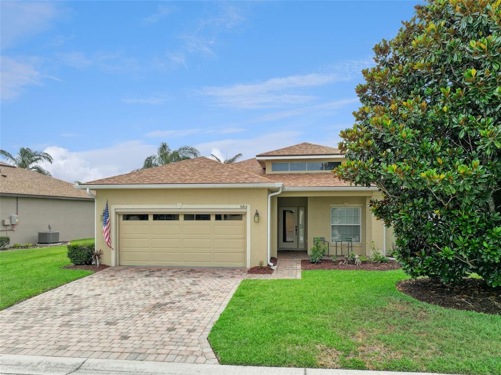 A single-story house with a tan stucco exterior, a two-car garage, and a paved driveway — 5312 NICKLAUS DRIVE, WINTER HAVEN, FL