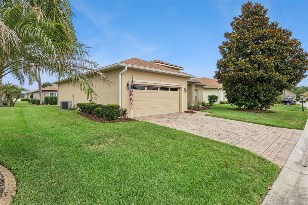 A beige single-story house with a two-car garage and a paved driveway — 5312 NICKLAUS DRIVE, WINTER HAVEN, FL