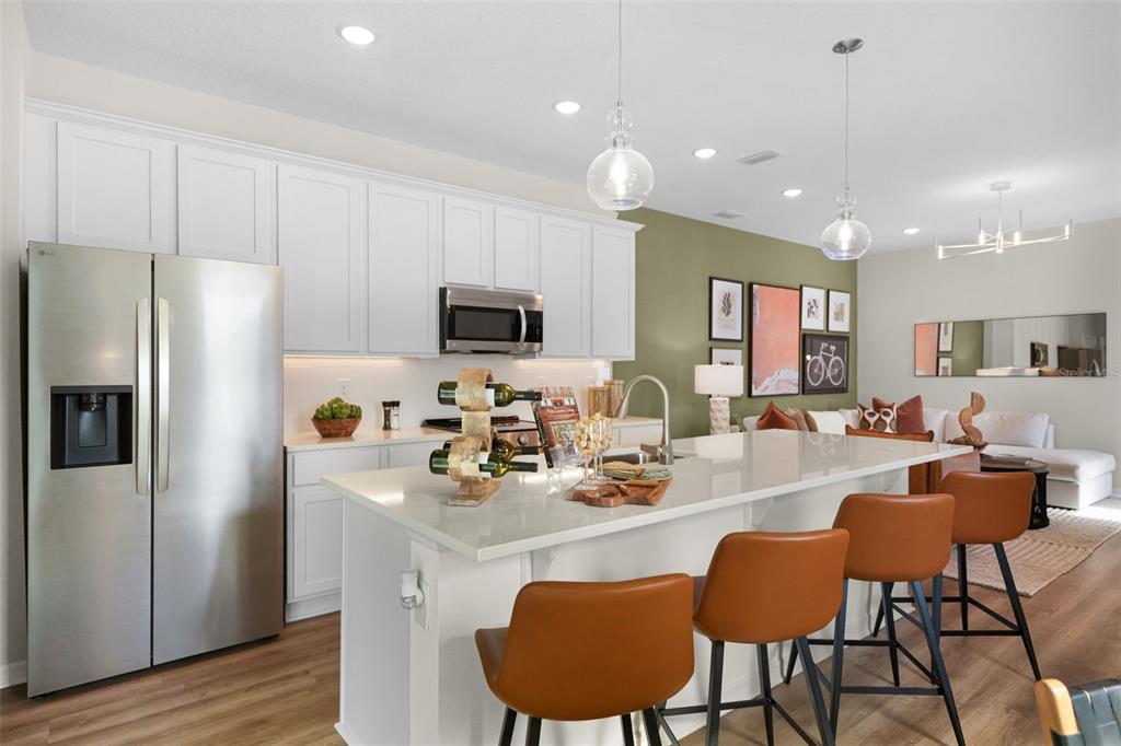 An open-concept kitchen and living area features a large island, wooden cabinets, and modern lighting — 4457 STARLING GROVE DRIVE, ORLANDO, FL