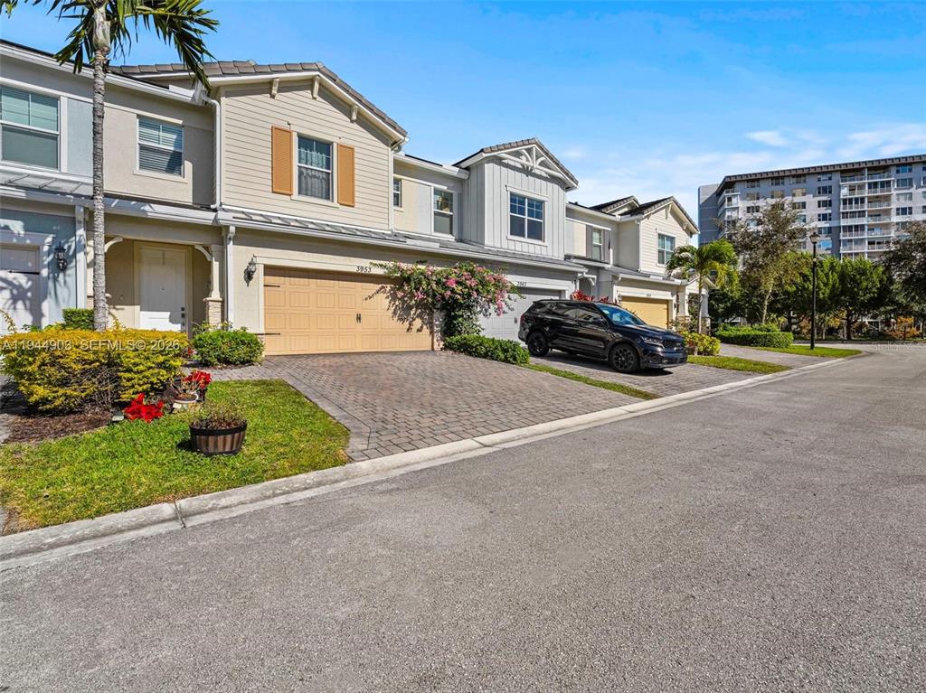 A row of two-story townhouses with tan siding, brick paver driveways, and a black SUV — 3953 BLACK OLIVE LANE, HOLLYWOOD, FL