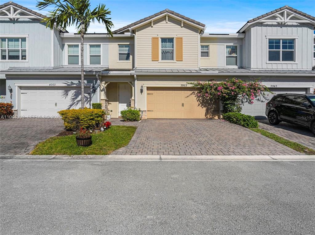 A three-story townhouse exterior features a tan garage, a paved driveway, and a palm tree — 3953 BLACK OLIVE LANE, HOLLYWOOD, FL
