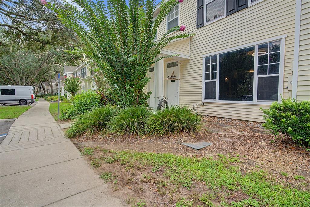 The exterior of a light yellow townhouse features a sidewalk, landscaping, and a large window — 2214 GOLDEN OAK LANE, VALRICO, FL