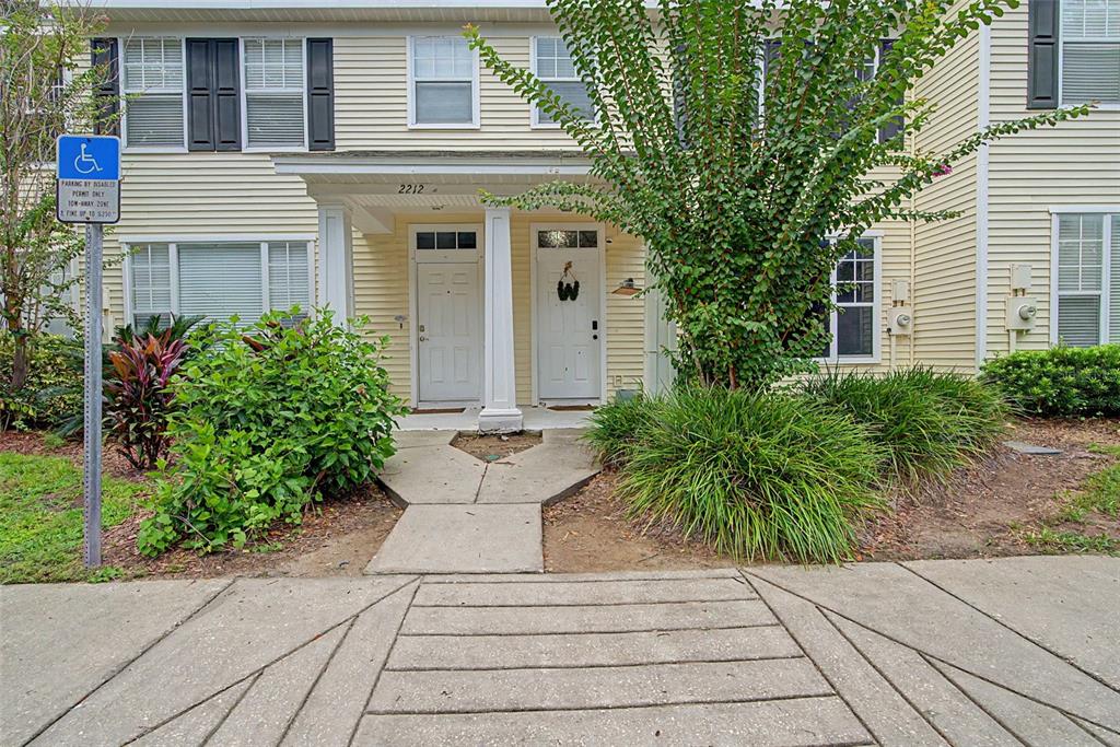 A two-story townhouse exterior features light yellow siding, two white front doors, and landscaping — 2214 GOLDEN OAK LANE, VALRICO, FL