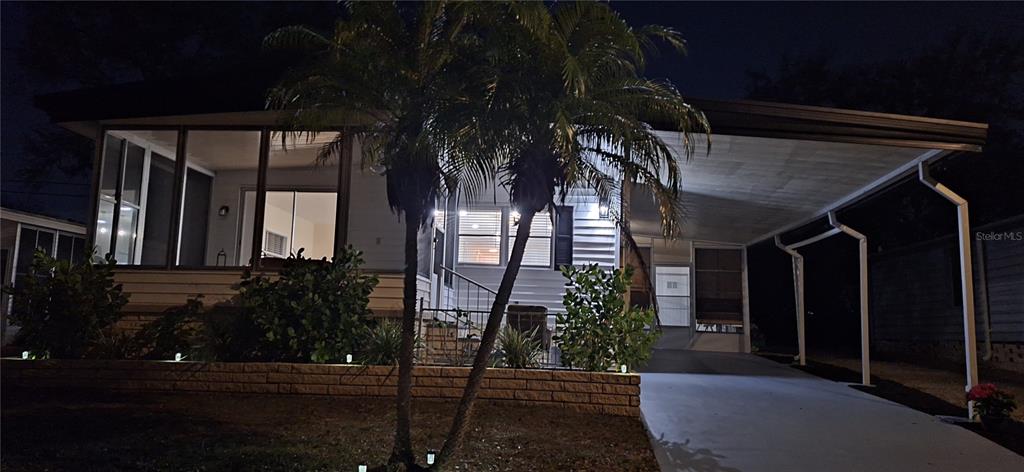 A single-story manufactured home with a screened porch, carport, and palm trees in the front — 50 DOGWOOD COURT UNIT 11, SAFETY HARBOR, FL