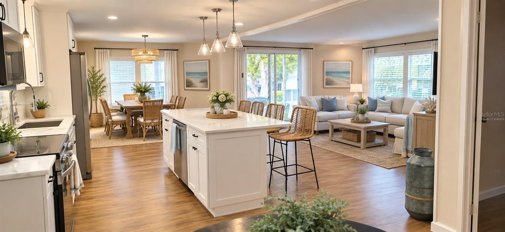 A modern kitchen features white cabinetry, stainless steel appliances, and a marble-topped island with stools — 50 DOGWOOD COURT UNIT 11, SAFETY HARBOR, FL