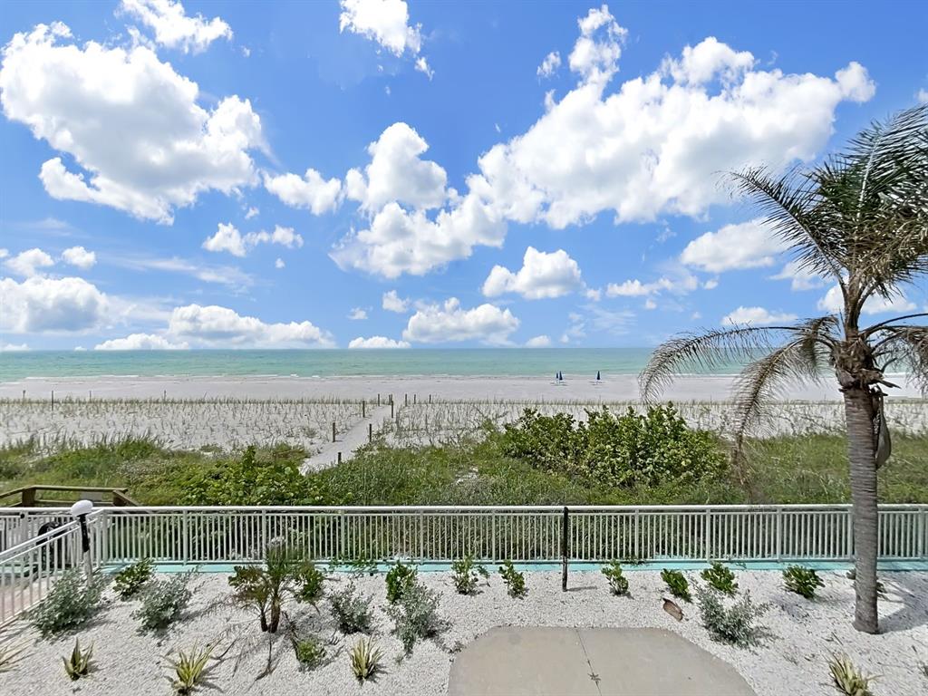 A view of a sandy beach and ocean from a balcony with a white railing — 19440 GULF BOULEVARD UNIT 104, INDIAN SHORES, FL