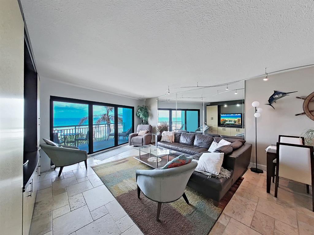 A living room with a large leather sectional, area rug, and an open-concept kitchen — 19440 GULF BOULEVARD UNIT 104, INDIAN SHORES, FL