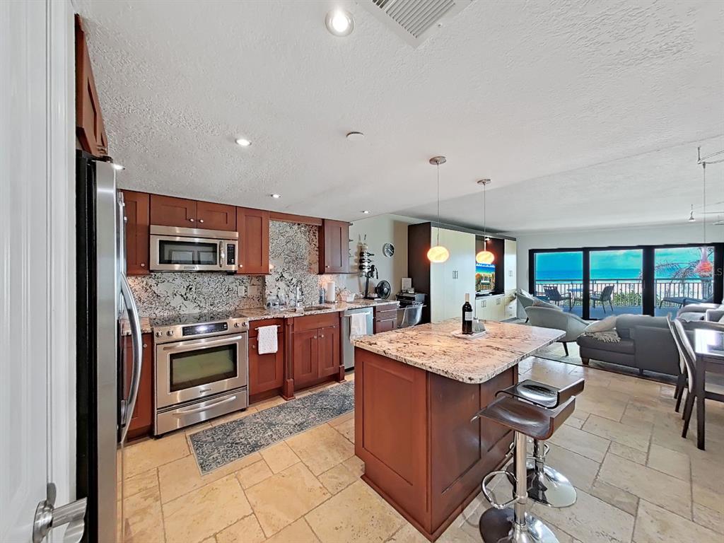 A living room with a large leather sectional, area rug, and an open-concept kitchen — 19440 GULF BOULEVARD UNIT 104, INDIAN SHORES, FL
